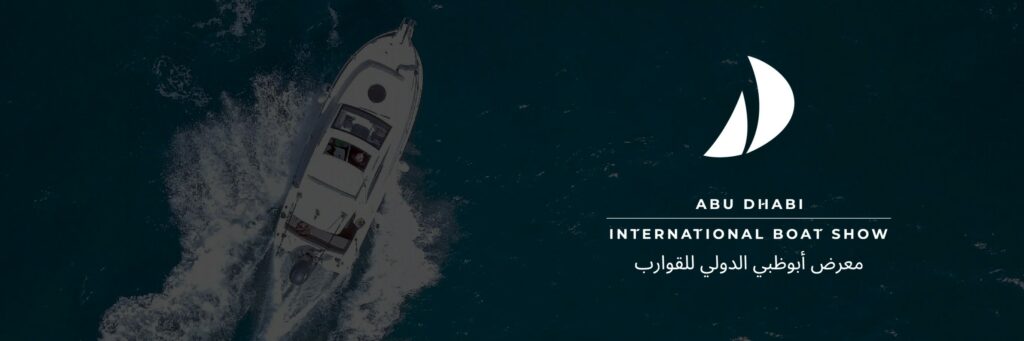 Fotografía nocturna de una lancha a motor navegando, con el logotipo del Abu Dhabi International Boat Show y texto en árabe