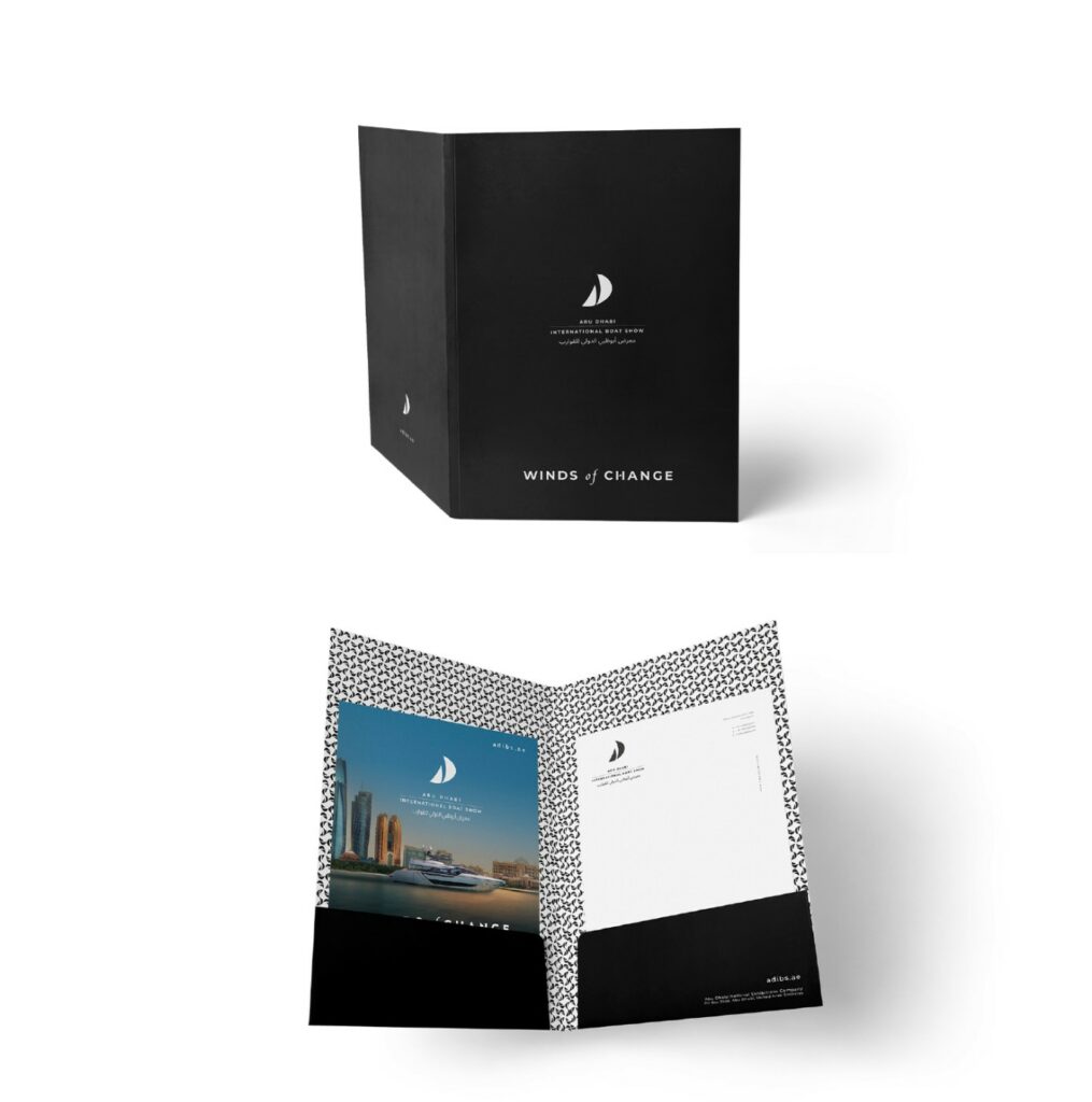 Carpeta negra con el logotipo y el lema "Winds of Change", abierta mostrando una fotografía de la marina y un forro con patrón de velas