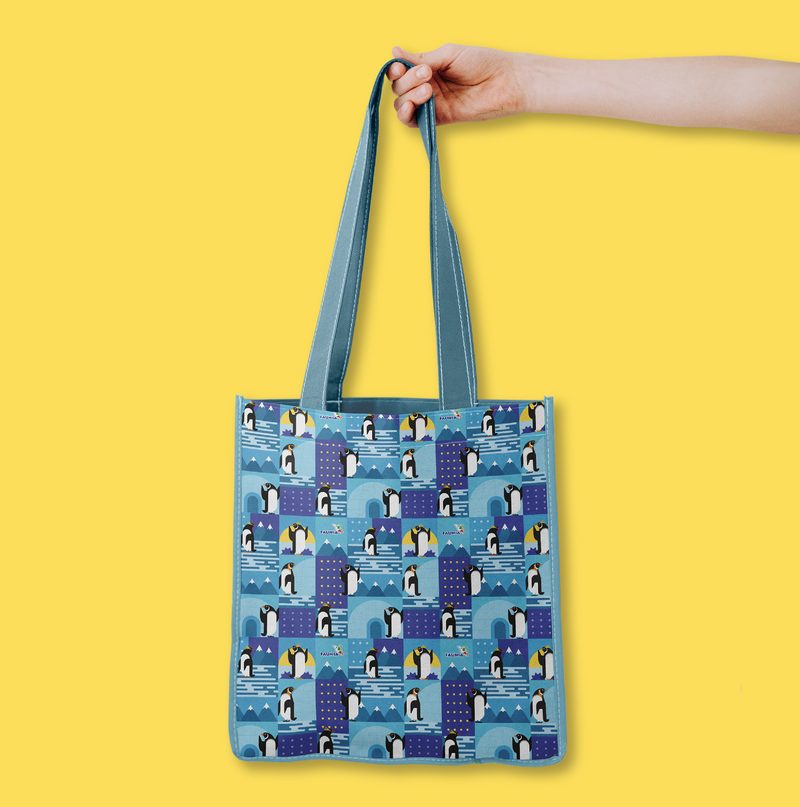 Bolsa amarilla con un patrón de pingüinos y el logotipo de Faunia