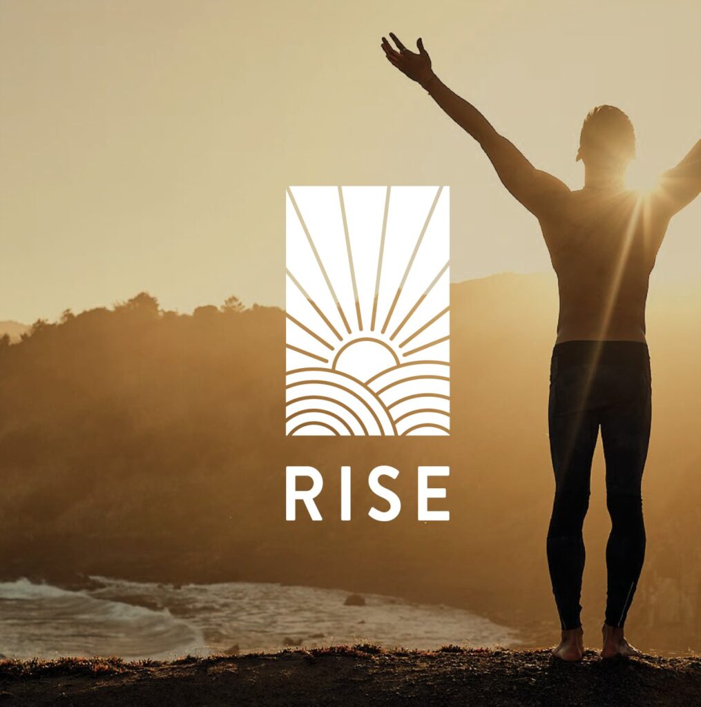 Fotografía de una persona con los brazos alzados frente al amanecer en la playa, con el logotipo RISE superpuesto