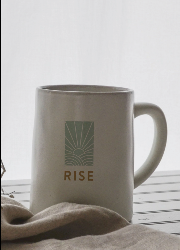 Taza de cerámica con el logotipo RISE sobre un fondo de arena de playa