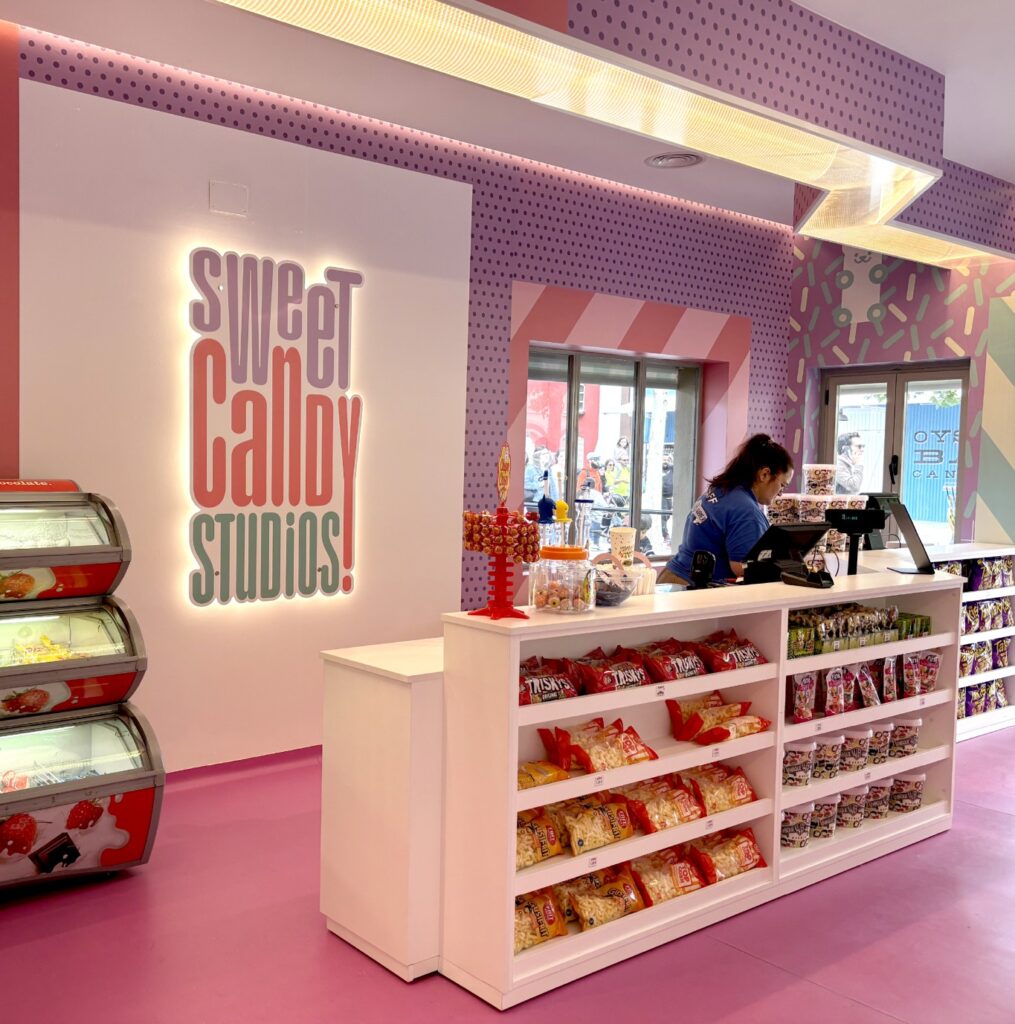 Interior de la tienda con estanterías rosas a rayas y una persona ojeando los dulces expuestos
