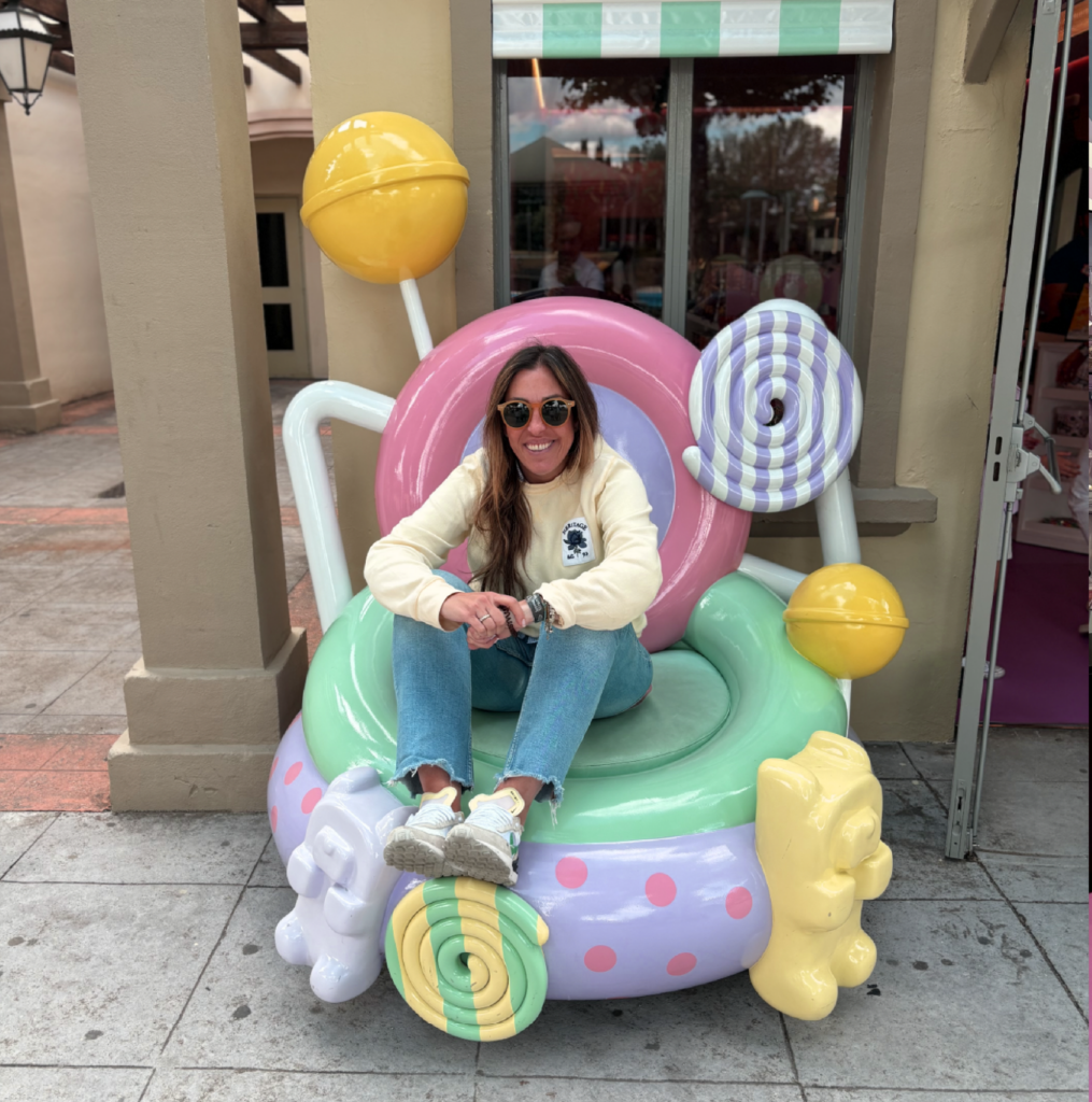 Fotografía de una persona sentada en un photocall con formas de dulces de colores