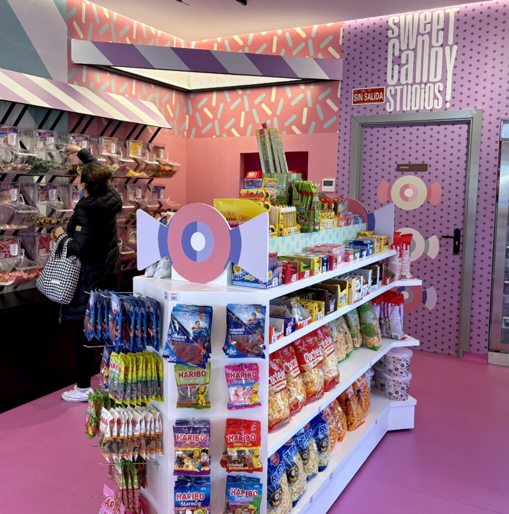Interior de la tienda con paredes rosas a rayas y estanterías de merchandising