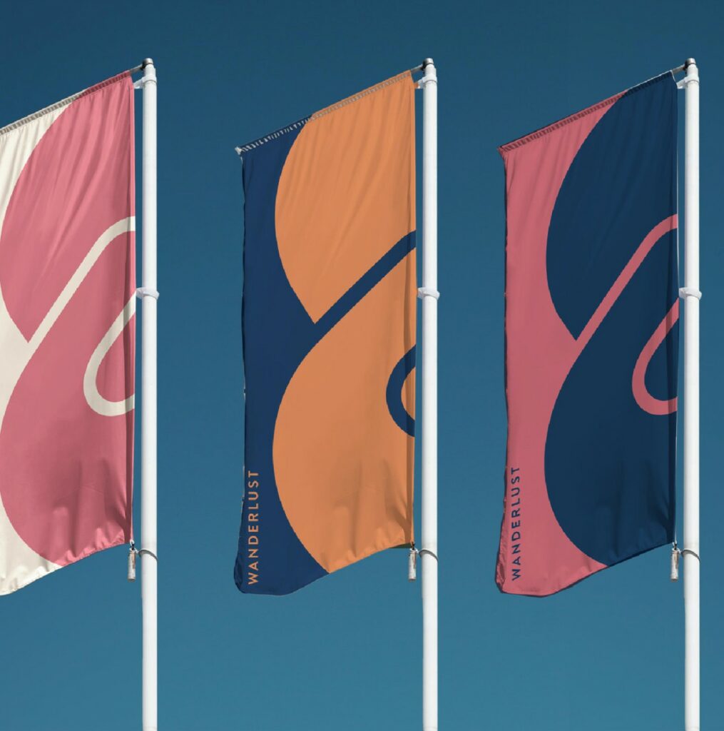 Tres banderas con el logotipo Wanderlust ondeando al aire libre contra un cielo azul
