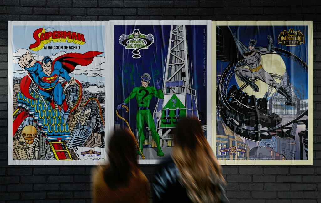 Tres carteles ilustrados de Superman, Linterna Verde y Batman expuestos en una pared de ladrillo, con dos personas observando