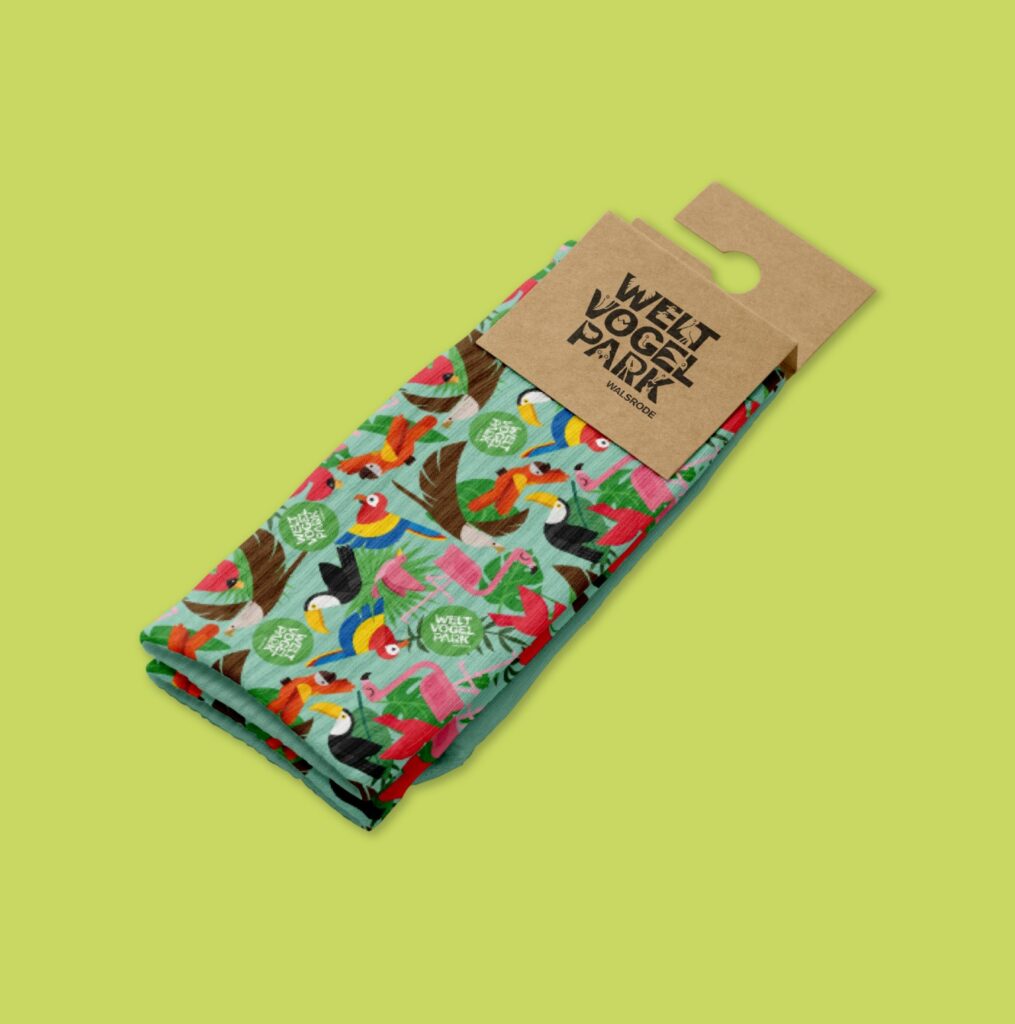 Bolsa de tela verde con un patrón de plumas y aves y el logotipo de Welt Vogel Park