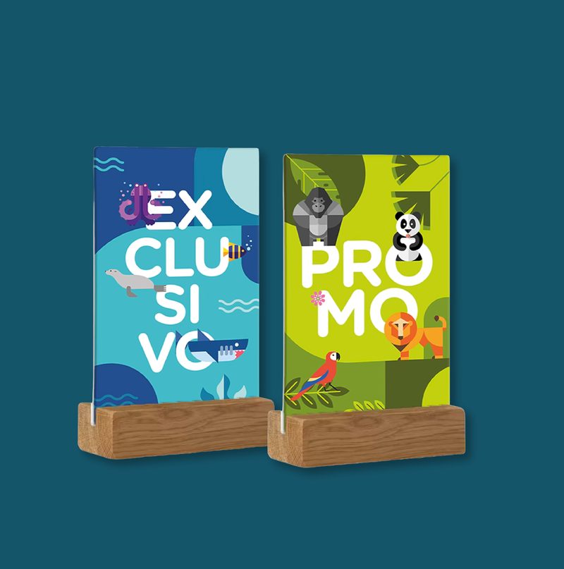 Dos expositores de sobremesa en madera con carteles "Exclusivo" (temática marina) y "Promo" (temática selva) del Zoo Aquarium Madrid