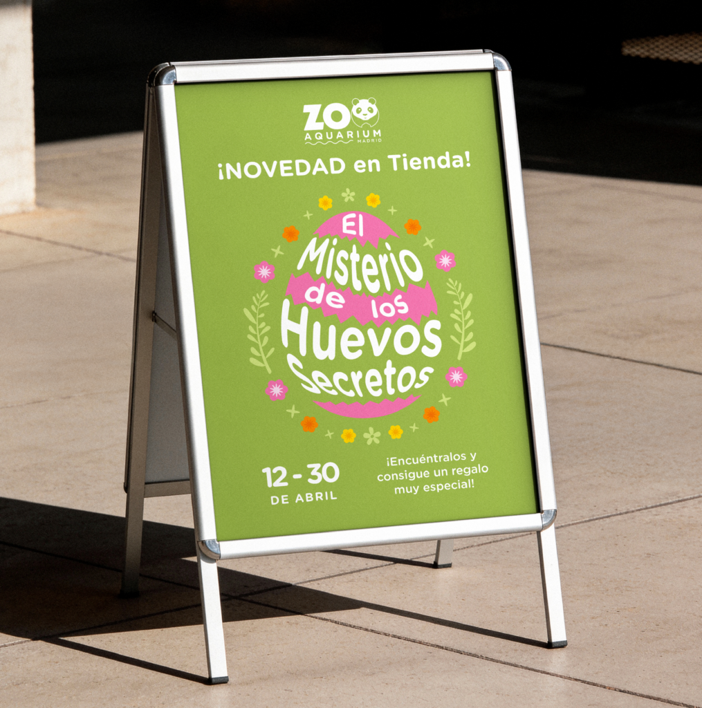 Cartel publicitario tipo caballete en la calle con el texto "El Misterio de los Huevos Secretos", fechas 12-30 de abril y premio especial