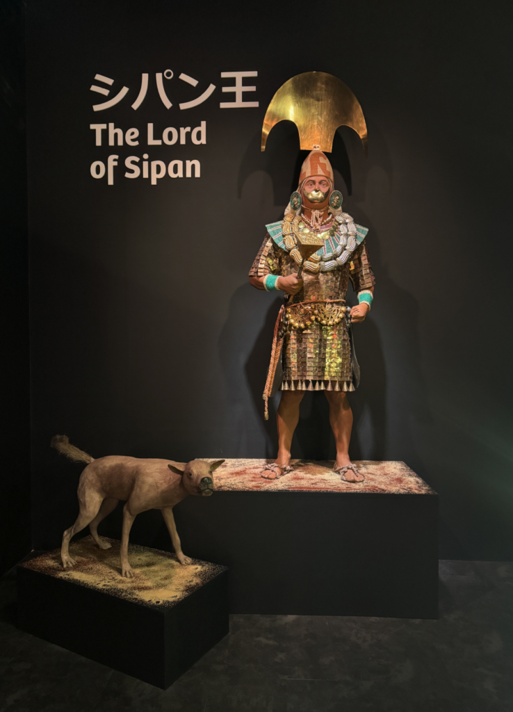 Exhibición "The Lord of Sipan" con una réplica del gobernante moche en atuendo ceremonial dorado, junto a una figura de perro